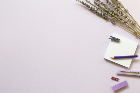Notepad, cutter, colored pencil, clip, lavender flowers on purple background. flat lay, top view,...
