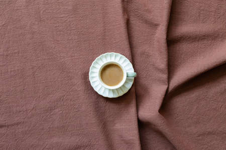 Cup of coffee on brown fabric background. top viewの写真素材