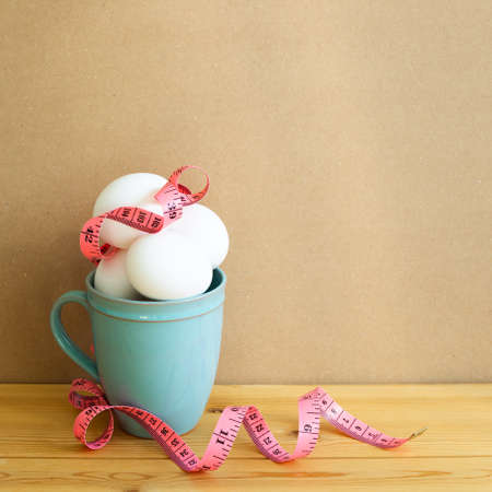 Egg with measuring tape on wooden table. brown background. Healthy food, Weight managementの写真素材
