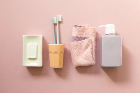 Spa bathroom products. Soap bar, toothbrush, towel, shampoo bottle on pink background. top viewの写真素材