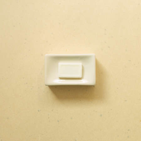 Soap bar in ceramic bowl on beige background. Bathroom. top viewの写真素材