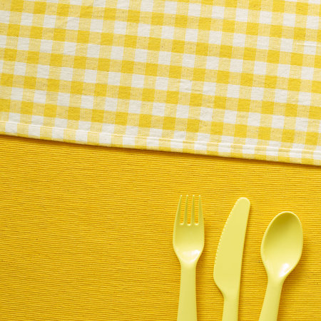 Fork knife spoon on yellow fabric background. top view, copy space