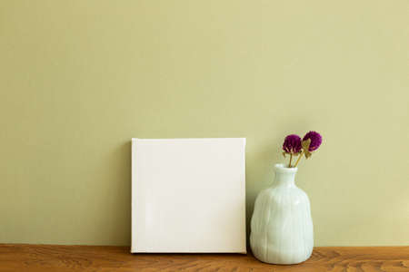 White canvas and vase of dry flowers on wooden table. khaki green background. copy spaceの写真素材