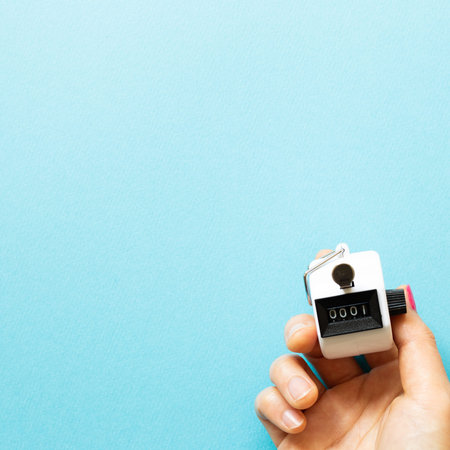 Hand tally counter on blue background. top view, copy space