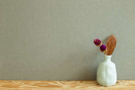 Vase of dry globe amaranth flowers on wooden table. Khaki gray backgroundの写真素材
