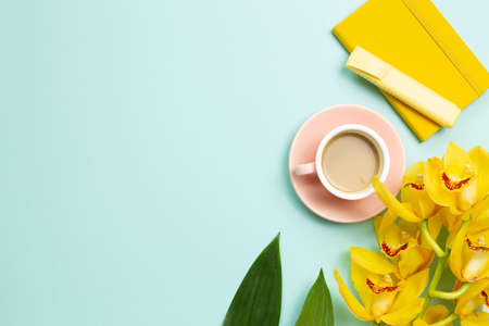 Yellow notebook, pen, cup of coffee, yellow flowers on blue background. flat lay, top view, copy spaceの写真素材