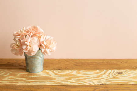 Vase of pastel pink carnation flowers on wooden tableの写真素材