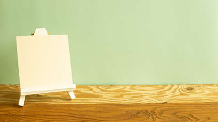 Easel with blank canvas on wooden table. green backgroundの写真素材
