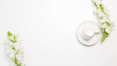 Coffee cup with white snapdragon flowers on white background. flat lay, top view, copy spaceの写真素材