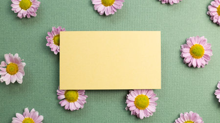 Blank memo pad with pink small flowered chrysanthemum on green background. flat lay, top view, copy...