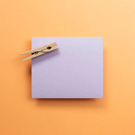 Purple memo pad with wooden clip on orange background. top view, copy spaceの写真素材