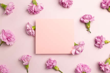Memo pad with carnation flowers on pink background. flat lay, top view, copy spaceの写真素材