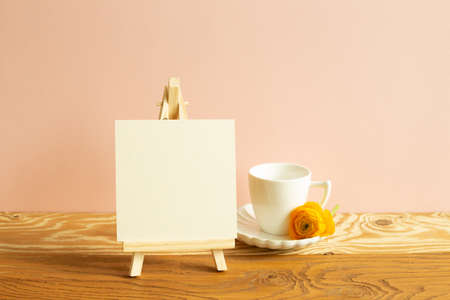 Easel and blank canvas with coffee cup on wooden table. pink backgroundの写真素材