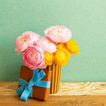 Brown gift box and ranunculus flowers bouquet on wooden table. green backgroundの写真素材