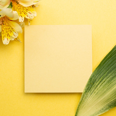 Memo pad with Alstroemeria flowers on yellow background. top view, copy space