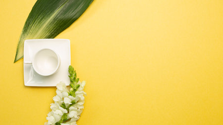 Empty coffee cup with flower on yellow background. flat lay, top view, copy spaceの写真素材