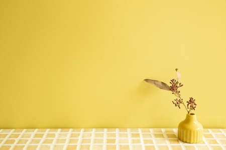 Vase of dry flowers on beige ceramic mosaic tile table. yellow wall background. home interiorの写真素材
