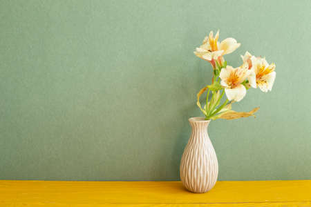 Vase of Yellow Alstroemeria flowers on wooden table. green backgroundの写真素材