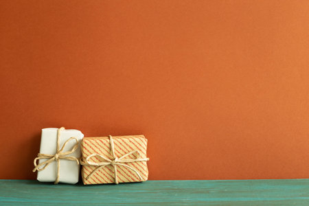 White and stripe pattern gift boxes on green wooden table. red wall backgroundの写真素材
