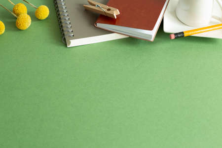 Notepad, pencil, wooden clip, coffee cup, dry flower on desk. green background. flat lay, top view, copy space. Work and study placeの写真素材