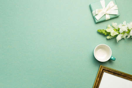 Gift box, white flower, cup, picture frame on green background. flat lay, top view, copy spaceの写真素材