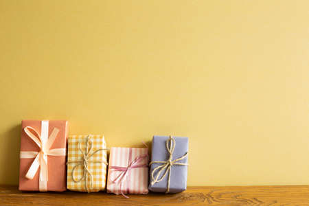 Colorful gift boxes on wooden table. yellow wall backgroundの写真素材