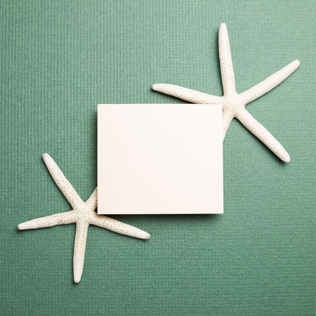 White blank memo pad and starfish on green background. summer marine decoration. top view, copy...