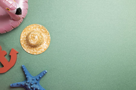 Summer vacation concept. Pink flamingo tube, straw hat, anchor, starfish on green background. flat...