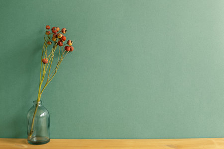 Vase of red dry flowers on wooden table. green wall background. home interiorの写真素材