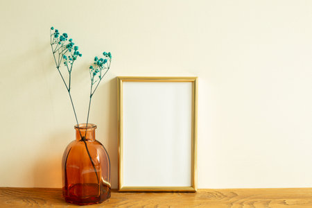 Gold photo frame and dry flowers on wooden table. beige wall background. home interior