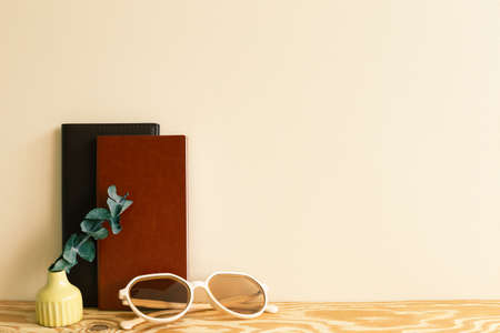 Notebook, glasses, eucalyptus on wooden desk. beige wall background. workspaceの写真素材