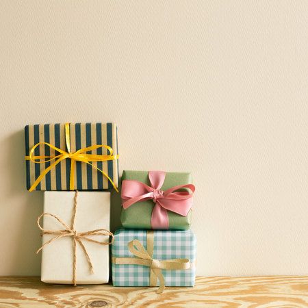 Stack of gift boxes on wooden table. beige wall background