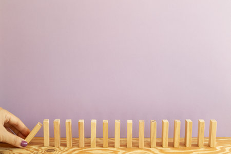 Wood domino blocks on desk. purple background. Domino effect business process conceptの写真素材