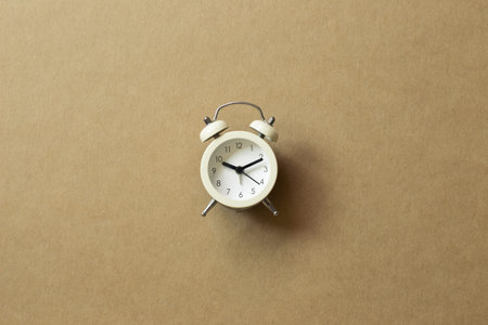White alarm clock on brown background. top view, copy space