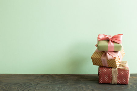 Stack of colorful gift boxes on wooden table. green wall backgroundの写真素材