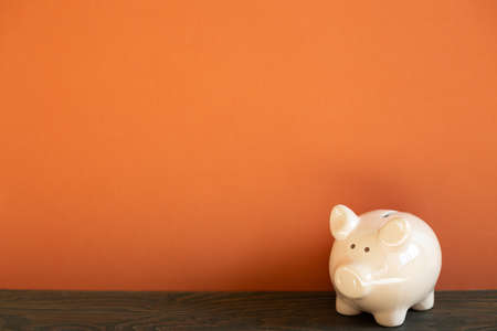 Pink piggy bank on wooden desk. red wall backgroundの写真素材