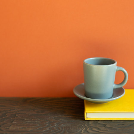 Yellow diary note book with cup of coffee on wooden desk. red wall backgroundの写真素材