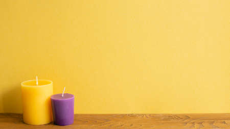 Color candles on wooden table. yellow wall background. home interiorの写真素材