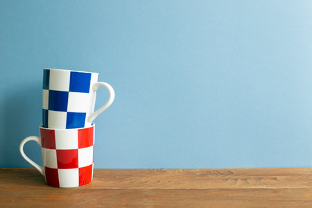 Stack of check pattern mug cup on wooden table. blue wall background. copy space