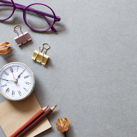 Memo pad, pencil, clock, clip, glasses on gray background. workspace. flat lay, top view, copy space