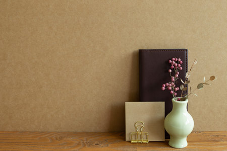 Diary, note pad, clip, dry flowers on wooden desk. brown wall backgroundの写真素材