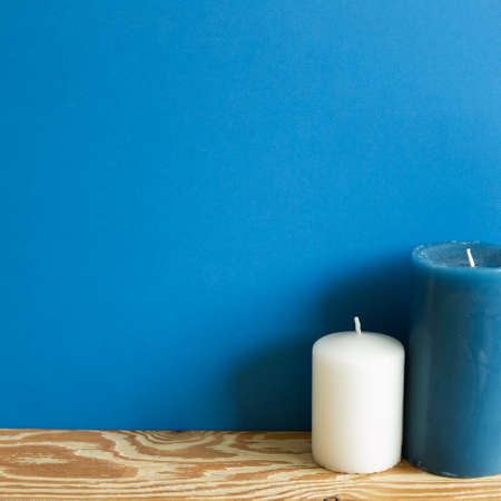 White and blue candle on wooden table. blue wall background. copy spaceの写真素材