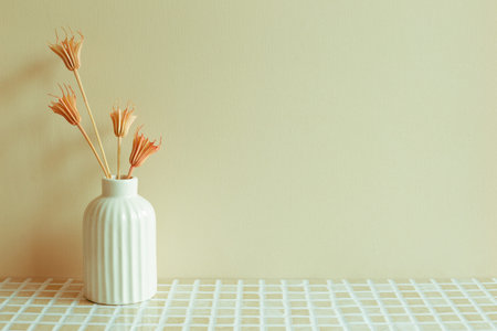 Vase of pink dry flowers on ceramic mosaic tile table. beige wall background. home interior
