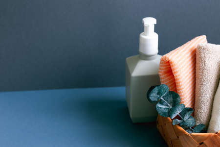 Soap dispenser and bathroom towel in basket on table. navy blue wall backgroundの写真素材