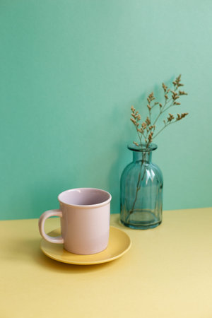 Purple mug cup and dry flowers on yellow table. green wall background. home interior