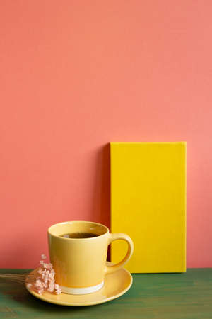 Yellow notebook and cup of coffee on green wooden table. pink wall background. copy spaceの写真素材