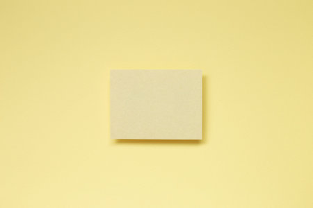 Yellow blank memo paper on yellow background. top view, copy space
