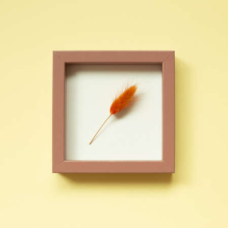 Pink picture frame with dry flower on yellow background. top view, copy spaceの写真素材