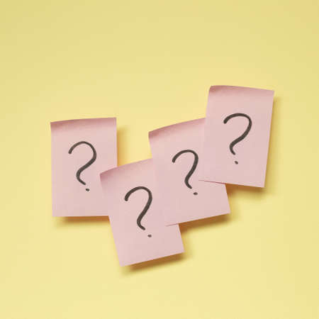 Question mark on pink memo paper on yellow backgroundの写真素材