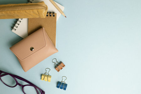 Notepad, clip, pencil, pouch, pencil case, glasses on blue background. flat lay, top view, copy...